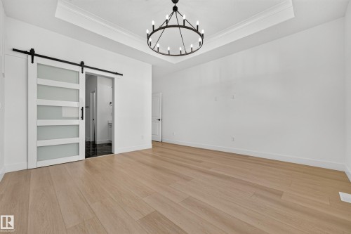 Light-toned wood-finish flooring complements the crisp white walls and crown molding - 11010 174A Avenue Nw, Edmonton, AB 