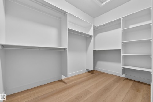 Walk-in closet with multiple hanging rods, extensive shelving, and wood-finish flooring - 11010 174A Avenue Nw, Edmonton, AB 