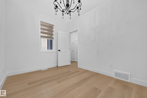 Light wood-finish flooring, white walls, and a black wrought-iron chandelier - 11010 174A Avenue Nw, Edmonton, AB 
