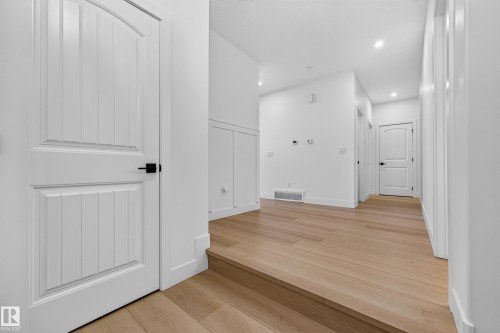 Light wood-finish flooring, white walls, recessed lighting, and white paneled doors with black hardware - 11010 174A Avenue Nw, Edmonton, AB 