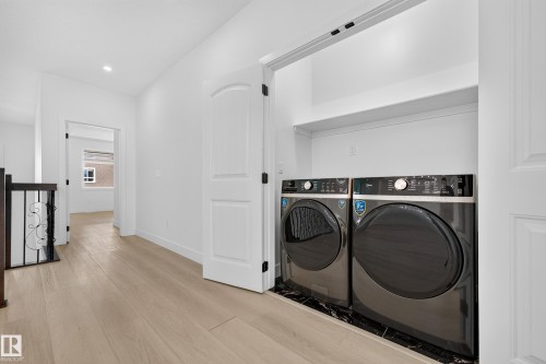 Dedicated laundry closet featuring a stacked washer and dryer, finished with a black marble-style base - 11010 174A Avenue Nw, Edmonton, AB 