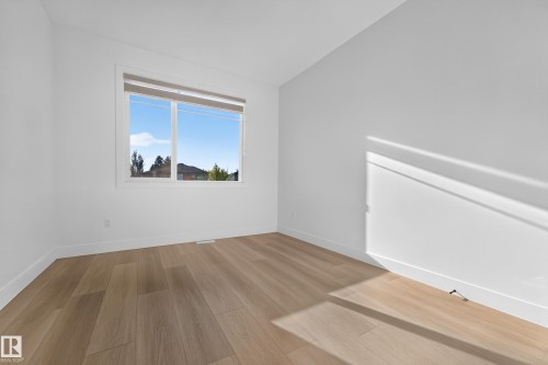 White walls, wood-finish flooring, and a large window - 11010 174A Avenue Nw, Edmonton, AB 