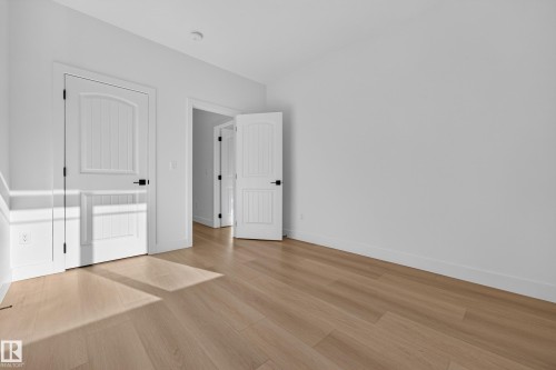 Wood-finish flooring throughout, bright white walls, and paneled interior doors with matte black hardware - 11010 174A Avenue Nw, Edmonton, AB 