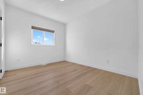 Bright interior with wood-finish flooring and a single window featuring a roller shade - 11010 174A Avenue Nw, Edmonton, AB 