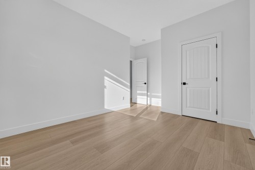 Light wood-finish flooring, white walls, and white interior doors with black hardware - 11010 174A Avenue Nw, Edmonton, AB 