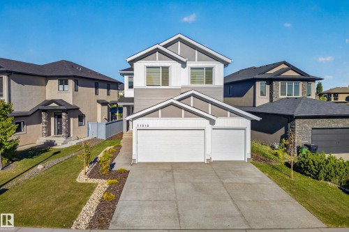 Two-car attached garage, paved driveway, landscaped front yard with decorative rock and plantings, and a two-story exterior with mixed siding materials - 11010 174A Avenue Nw, Edmonton, AB 