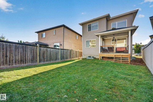 Expansive rear yard featuring a covered wooden deck, modern exterior siding, and a wooden privacy fence - 11010 174A Avenue Nw, Edmonton, AB 