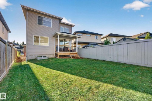 Expansive grassy backyard featuring a covered patio with wood decking, direct access to the interior, and full perimeter fencing - 11010 174A Avenue Nw, Edmonton, AB 