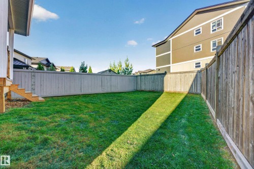 Expansive backyard featuring a manicured lawn, full perimeter fencing, and exterior stairs providing access to the residence - 11010 174A Avenue Nw, Edmonton, AB 