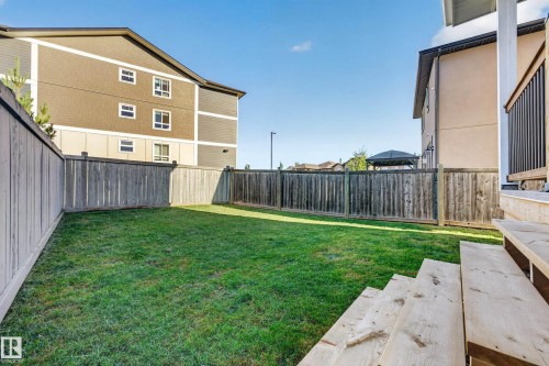 Fenced backyard with natural wood fencing, a manicured lawn, and exterior stairs with wood treads - 11010 174A Avenue Nw, Edmonton, AB 