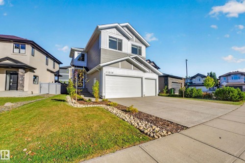 Modern two-story residence with a two-car attached garage, featuring a paved driveway, a manicured front lawn, and a stone-lined garden bed - 11010 174A Avenue Nw, Edmonton, AB 