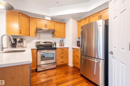 Kitchen featuring wood-finish cabinetry, stainless steel appliances, white subway tile backsplash, and light-toned countertops - #230 45 Inglewood Dr, St. Albert, AB 