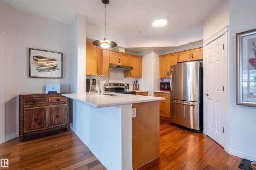 Kitchen featuring wood-finish flooring, stainless steel appliances, light-toned cabinetry, a built-in kitchen island, and recessed lighting - #230 45 Inglewood Dr, St. Albert, AB 