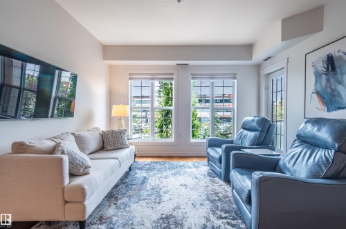 Wood-finish flooring, multiple large windows with roller shades, and a glass-paneled door - #230 45 Inglewood Dr, St. Albert, AB 
