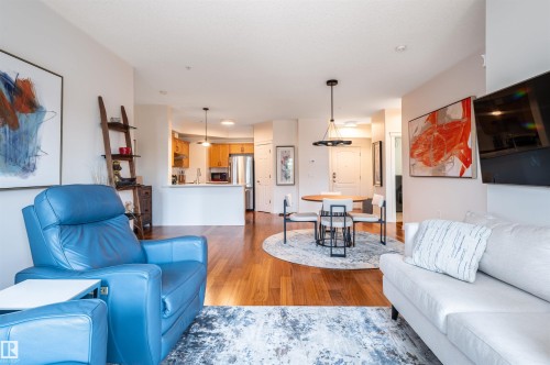 Open concept living area featuring wood-finish flooring, a kitchen with wood cabinetry and stainless steel appliances, and a dining area with a contemporary light fixture - #230 45 Inglewood Dr, St. Albert, AB 