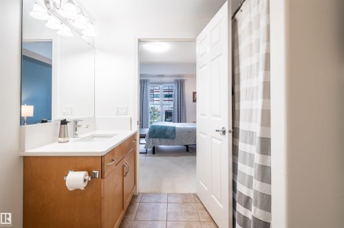 Bathroom featuring a single vanity with wood-finish cabinetry, a white countertop, and a large wall-mounted mirror - #230 45 Inglewood Dr, St. Albert, AB 