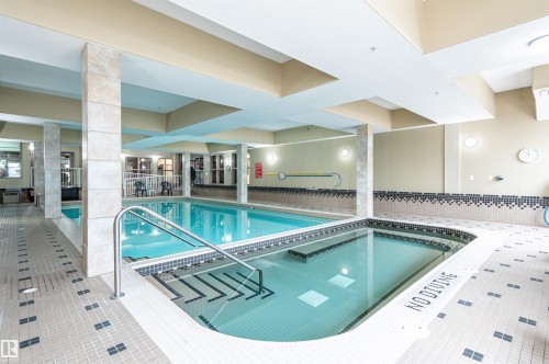 Indoor pool with a separate spa, surrounded by tiled decking and textured wall accents - #230 45 Inglewood Dr, St. Albert, AB 