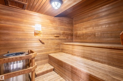 Wood-paneled sauna featuring a built-in heater, tiered seating, and integrated overhead lighting - #230 45 Inglewood Dr, St. Albert, AB 