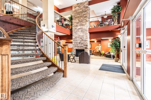Grand two-story lobby featuring a curved staircase with wood banister and wrought iron spindles - #230 45 Inglewood Dr, St. Albert, AB 