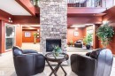 Stone-clad fireplace feature with an integrated hearth, tiled flooring, and a second-story balcony with metal railings - #230 45 Inglewood Dr, St. Albert, AB 