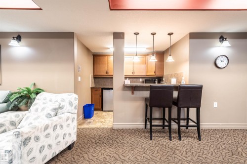 Built-in wet bar with pendant lighting, wood cabinetry, and a textured countertop - #230 45 Inglewood Dr, St. Albert, AB 