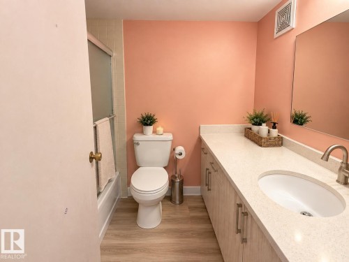 Wood-finish flooring, vanity with light-toned countertop, oval undermount sink, and brushed nickel faucet - #108 2624 Mill Woods Rd E Nw, Edmonton, AB 