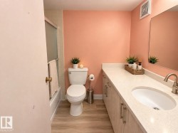 Wood-finish flooring, vanity with light-toned countertop, oval undermount sink, and brushed nickel faucet - 
