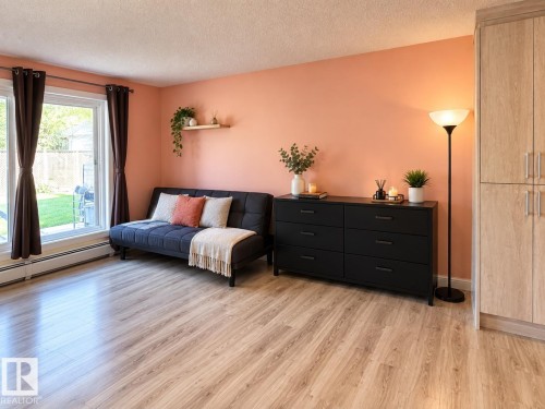 Wood-finish flooring throughout, complemented by a large window with white trim - #108 2624 Mill Woods Rd E Nw, Edmonton, AB 