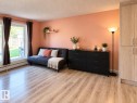 Wood-finish flooring throughout, complemented by a large window with white trim - #108 2624 Mill Woods Rd E Nw, Edmonton, AB 