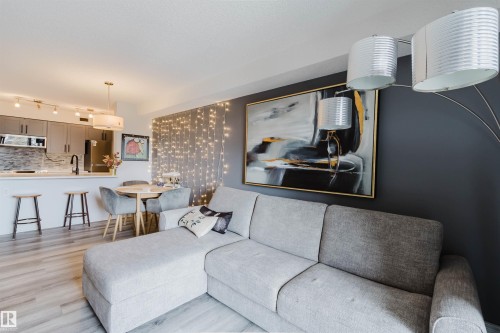 This open-concept living space features light wood-look flooring, a kitchen with grey cabinetry and a white countertop, and an integrated dining area - #204 11803 22 Av Sw, Edmonton, AB 