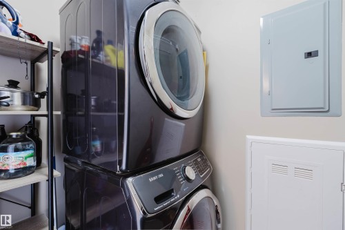 This utility area includes a stacked washer and dryer, along with wall-mounted electrical panels - #204 11803 22 Av Sw, Edmonton, AB 
