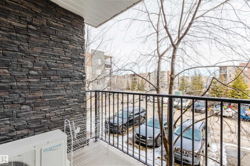 The property features a balcony with a black metal railing, offering views of parked vehicles - #204 11803 22 Av Sw, Edmonton, AB 