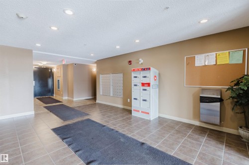 The property features a well-maintained common area with tiled flooring, recessed lighting, and a neutral wall color - #204 11803 22 Av Sw, Edmonton, AB 