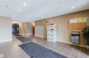 The property features a well-maintained common area with tiled flooring, recessed lighting, and a neutral wall color - #204 11803 22 Av Sw, Edmonton, AB 