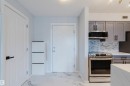 The property features a kitchen with grey cabinetry, stainless steel appliances, and a tiled backsplash - #204 11803 22 Av Sw, Edmonton, AB 
