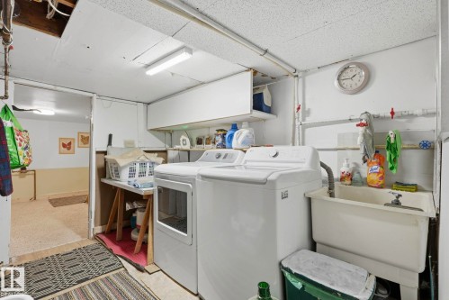 Laundry area featuring a utility sink, open shelving, and overhead lighting - 9628 100A Street Nw, Edmonton, AB 