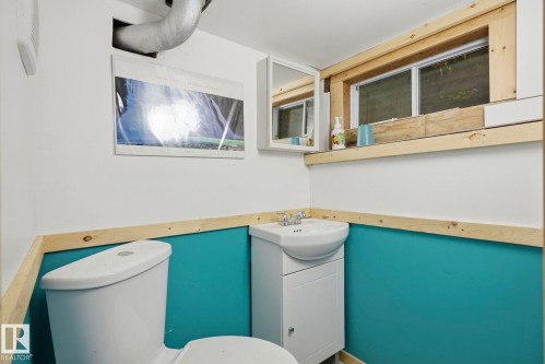 White toilet with a wall-mounted sink vanity, integrated storage, and a framed window - 9628 100A Street Nw, Edmonton, AB 