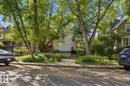 White siding exterior featuring a covered entry and mature front yard landscaping - 9628 100A Street Nw, Edmonton, AB 
