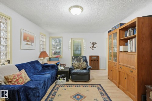 Recessed ceiling light fixture, wood-finish flooring, multiple windows, built-in wooden cabinetry with glass doors, and a built-in wooden desk unit - 9628 100A Street Nw, Edmonton, AB 
