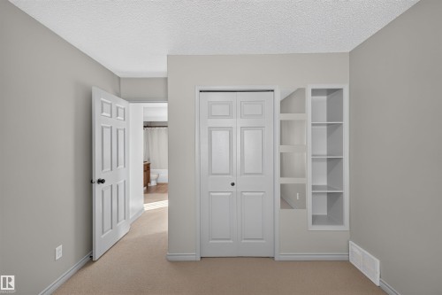 Wall-to-wall carpeting with built-in shelving and a bi-fold closet - 6116 8 Avenue Sw, Edmonton, AB 