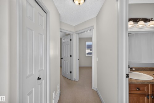 Recessed ceiling light fixture, white six-panel doors, carpeted flooring, wood vanity with integrated sink, and a multi-bulb vanity light fixture - 6116 8 Avenue Sw, Edmonton, AB 