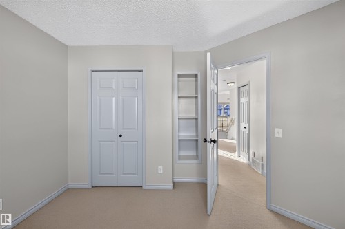 Built-in shelving, neutral-toned carpeting, and a bi-fold closet door - 6116 8 Avenue Sw, Edmonton, AB 