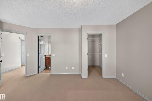 Carpeted room with neutral wall tones and a built-in closet with shelving - 6116 8 Avenue Sw, Edmonton, AB 