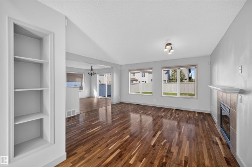 Wood-finish flooring, built-in shelving, tiled fireplace with mantel, recessed lighting, and multiple windows - 6116 8 Avenue Sw, Edmonton, AB 