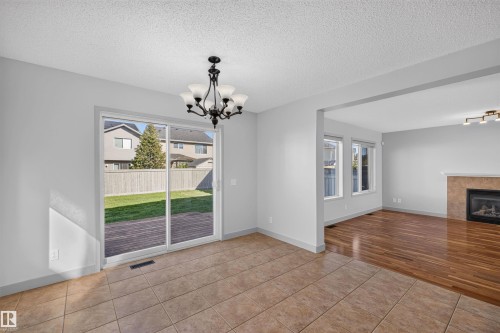 Tiled flooring with a sliding glass door to the exterior, featuring an overhead chandelier - 6116 8 Avenue Sw, Edmonton, AB 