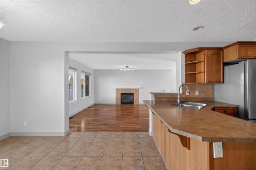 Kitchen featuring a stainless steel sink, wood cabinetry, and a stainless steel refrigerator - 6116 8 Avenue Sw, Edmonton, AB 
