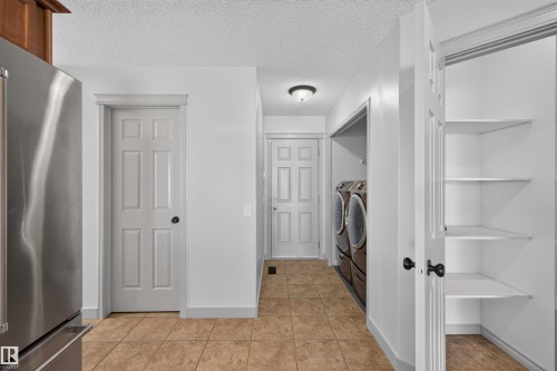 Tile flooring, built-in shelving, stainless steel refrigerator, and recessed lighting - 6116 8 Avenue Sw, Edmonton, AB 