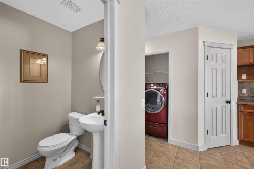 Pedestal sink with wall-mounted lighting, tiled flooring, and a paneled interior door - 6116 8 Avenue Sw, Edmonton, AB 