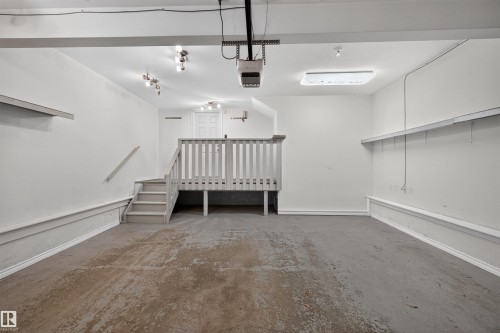Attached garage featuring a concrete floor, built-in shelving, and a raised wooden platform with stairs - 6116 8 Avenue Sw, Edmonton, AB 