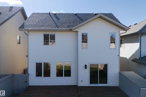 Rear exterior with white siding, dark shingle roof, and a wood-finish deck - 6116 8 Avenue Sw, Edmonton, AB 